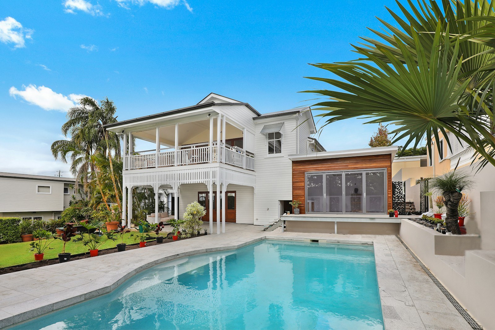 Piscina exterior y terraza junto a una casa.